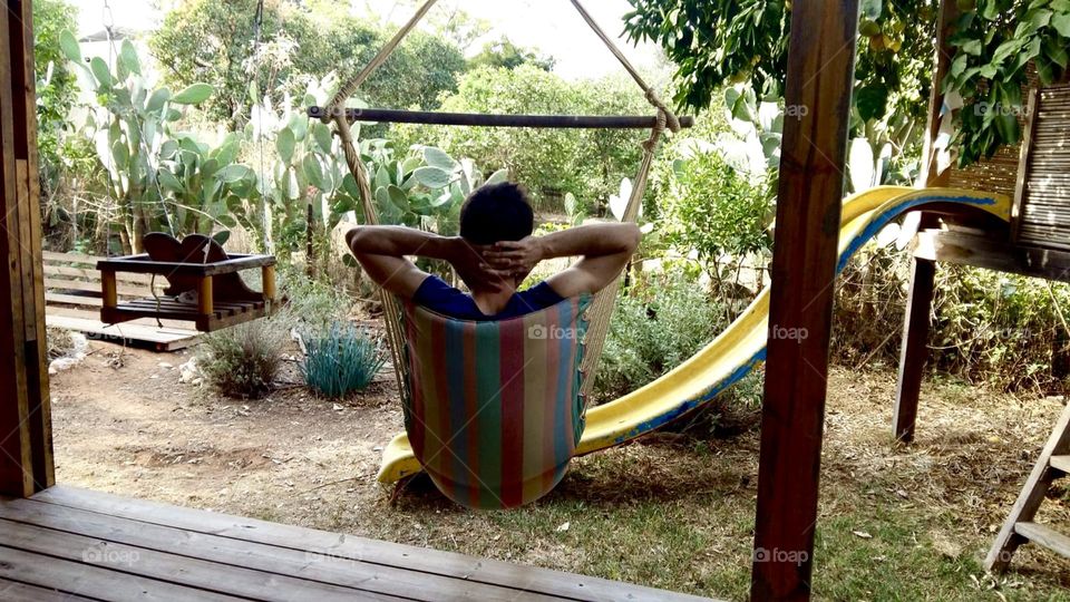 Man sitting on an hammock enjoying his backyard 