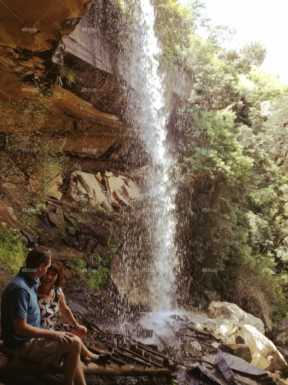 Married couple sitting near waterfall