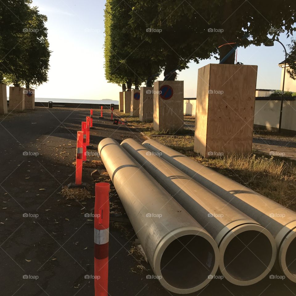 Three big water pipes ready for use at the end of the treelined street out to sea.