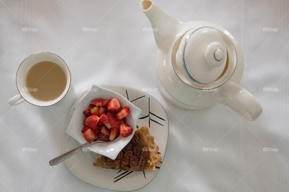Tea, strawberries and pecan pie beside a  in a festive flat lay