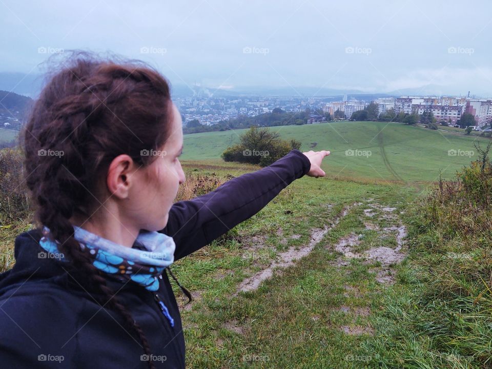 woman pointing her finger to the city from rainy hill