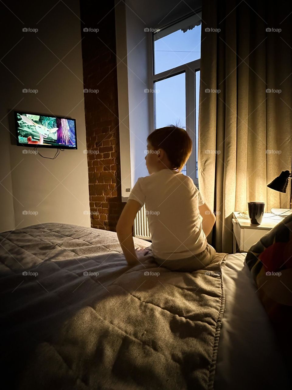 red-haired boy watching a movie in the evening at home