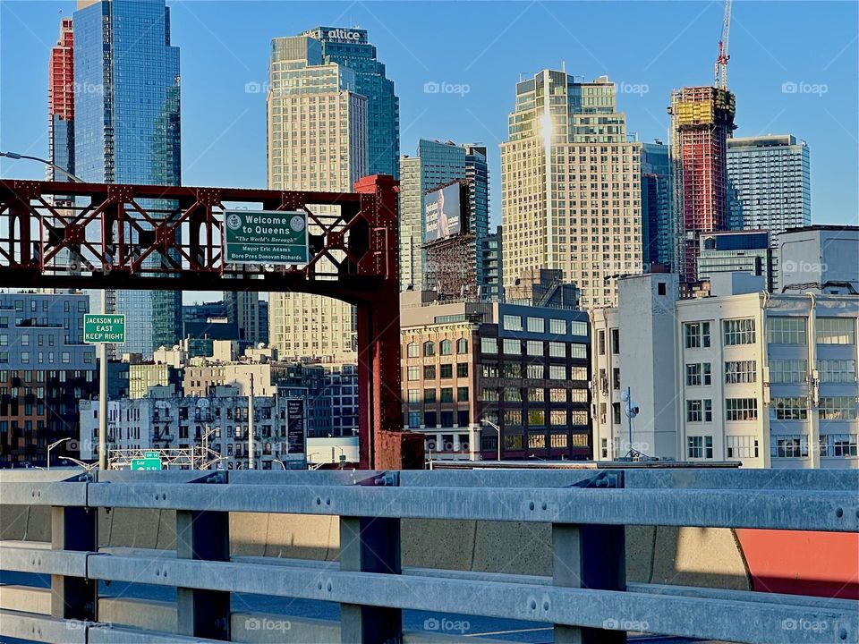 This is the “Pulaski Bridge” at “Newtown Creek” that connects “Greenpoint”, Bklyn to LIC, Queens, the direction we are facing. The setting sun bathes LIC in its warm glow and the NYC patterns merge with those of the bridge. 2024. Hypnotic Productions
