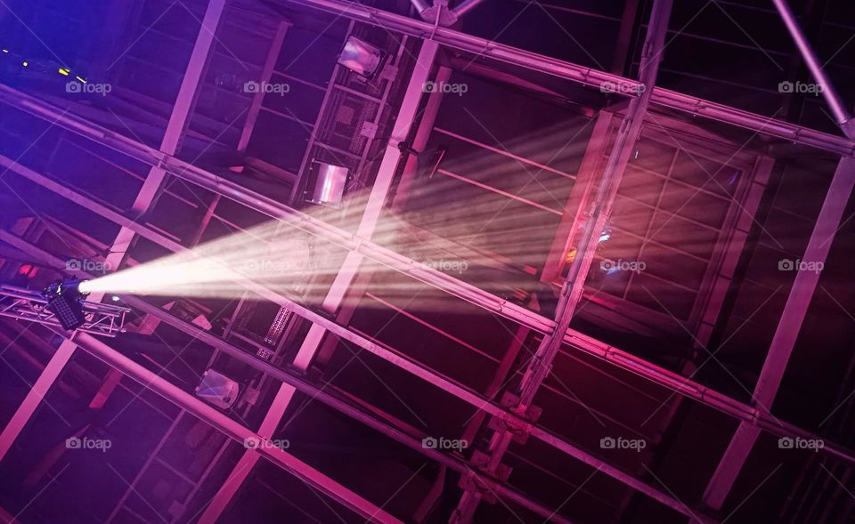 High angle view into a pink lightened metal construction and a single shining headlight