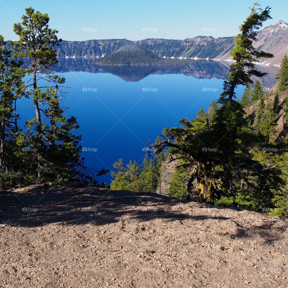 Wizard Island reflecting in the rich blue waters of Crater Lake in the forests of Southern Oregon on a sunny summer morning. 