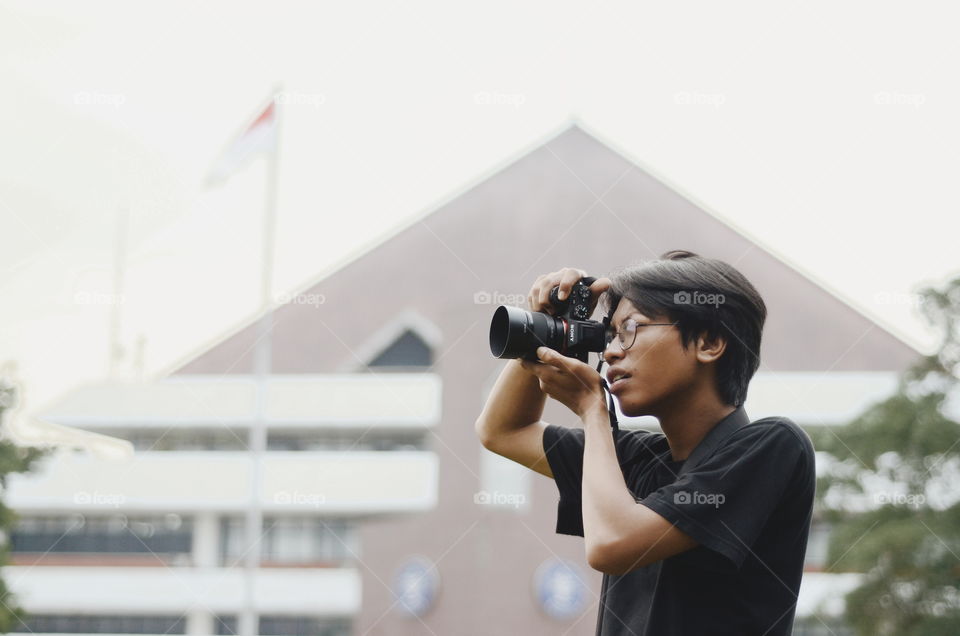 A boy with his photography hobby is enjoying the afternoon vibes while capturing some moments.