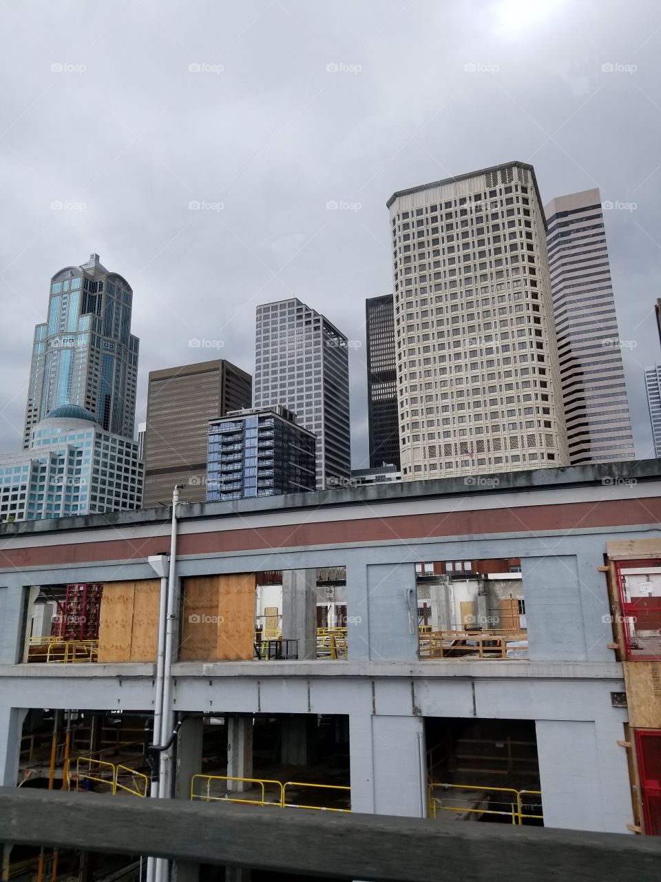 Contrast of finished Skyscrapers with boarded up windows of building in front May 17 2017 Seattle No edits