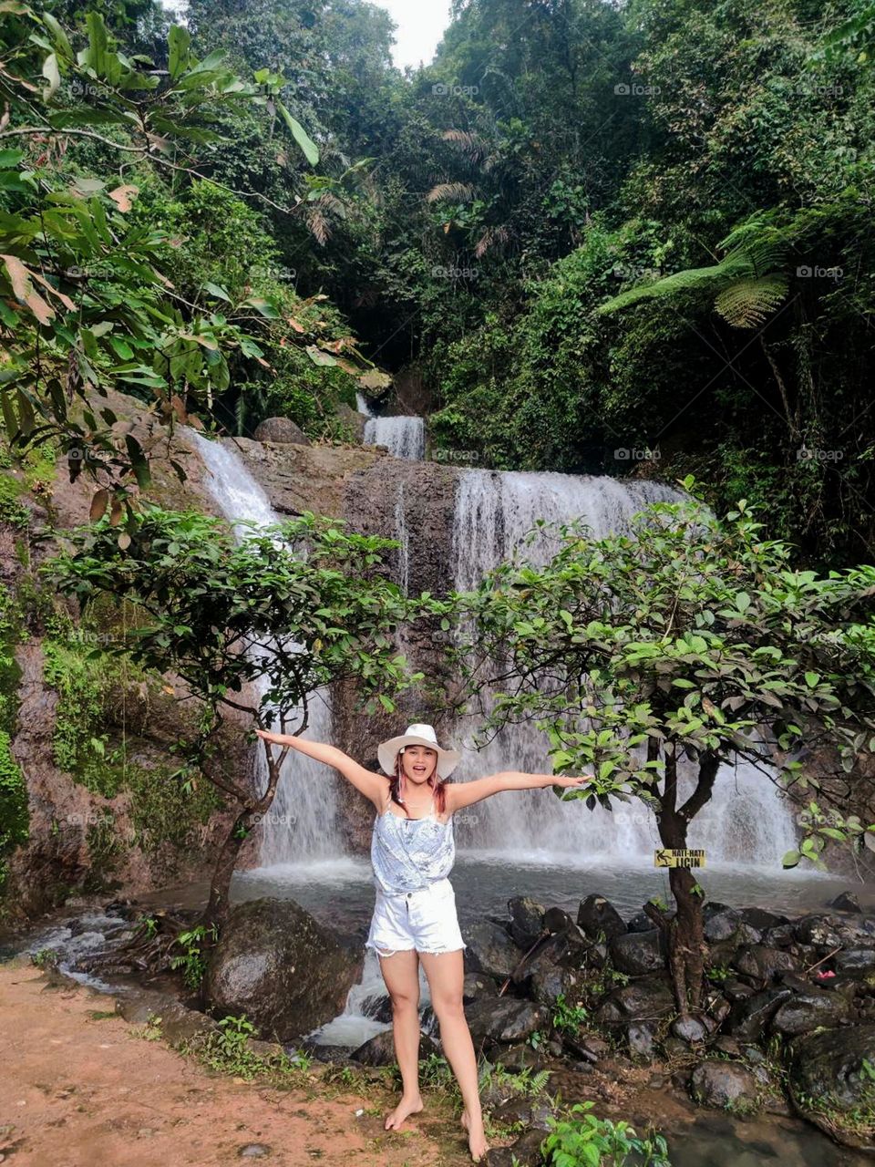 Portrait of woman standing against waterfall