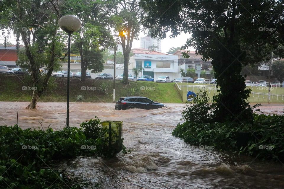 Car on a heavy rain day, on a flood, flooded street at Piracicaba, Brasil. 
Black car on the Waters of a flood in Brazil.