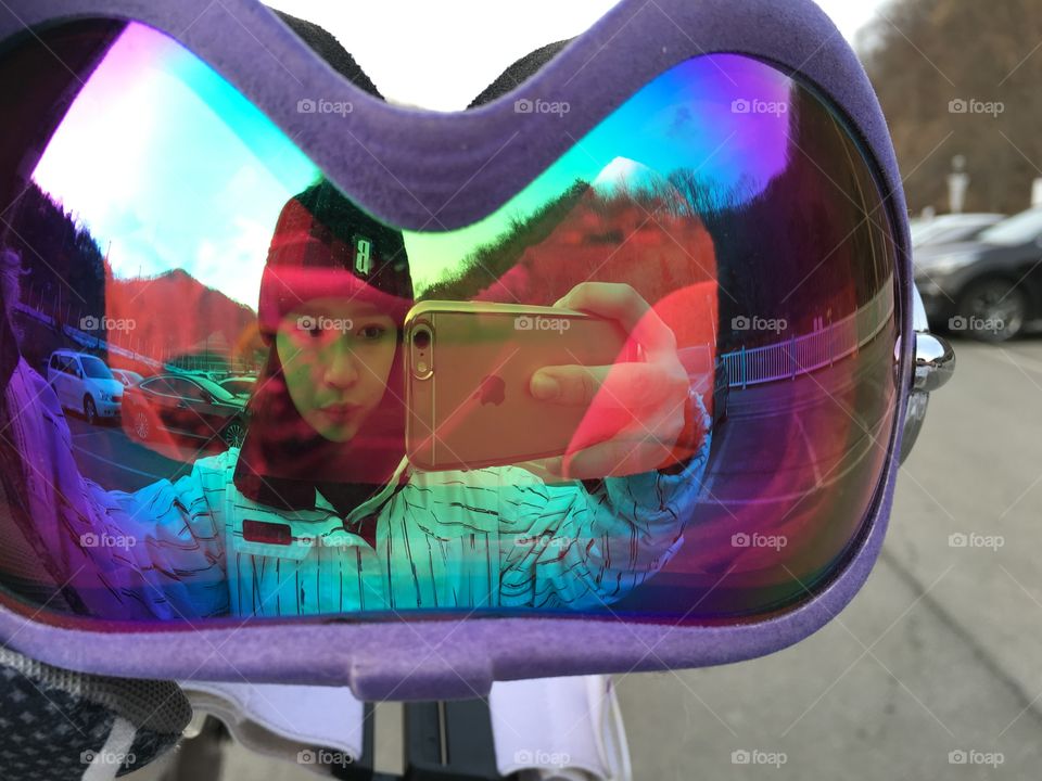 Woman taking selfie reflecting in ski goggles