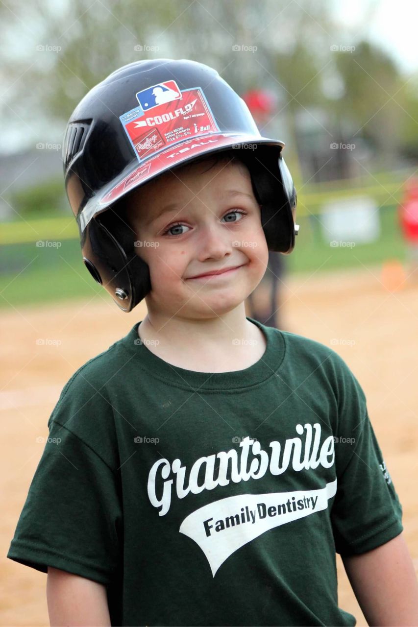 My sweet little boy getting ready to take his turn at bat, protecting his head with a batting helmet. 