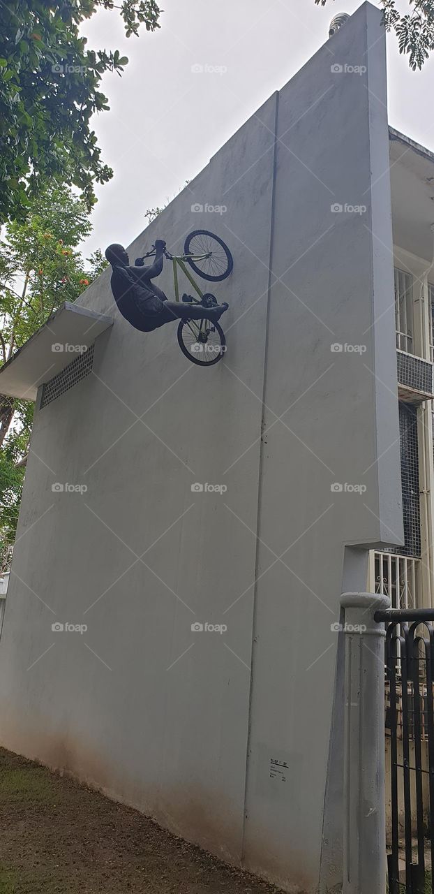 sculpture of a cyclist climbing the wall.  Located in the acoustic shell in Aragua Venezuela