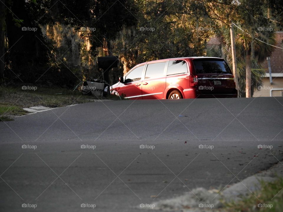 Commuting: car van driving up the road and turning at an intersection in the evening with the beautiful sunlight from the sunset shining on the Spanish moss and leaves from the live oak trees.