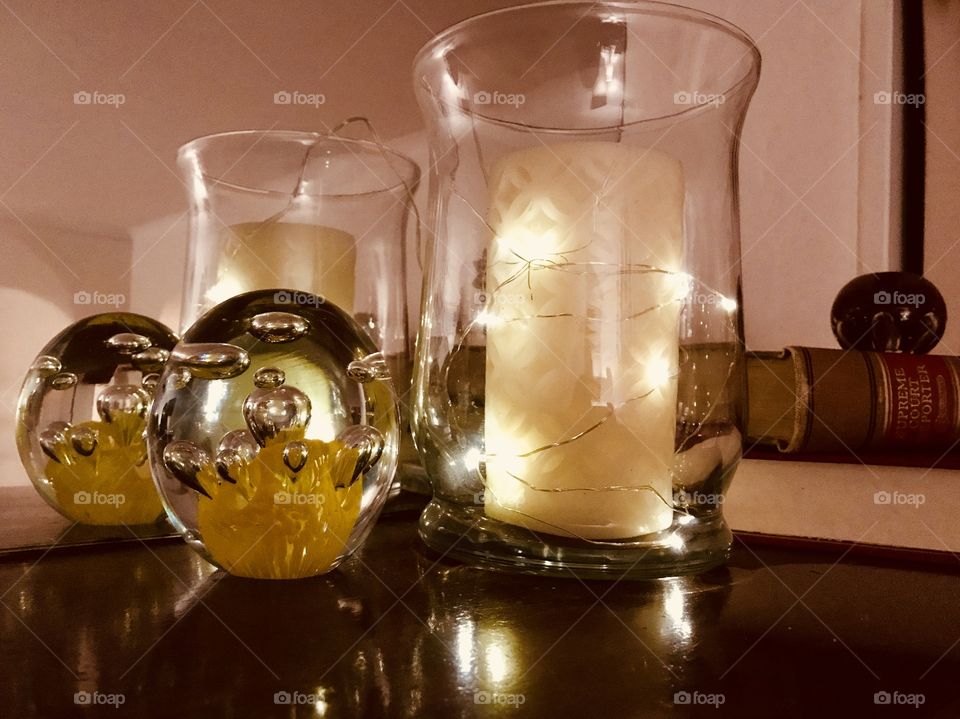 Fireplace mantel decor. Illuminated glass, candles, and paperweight in front of mirror 