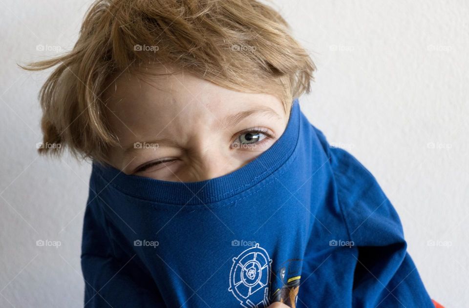 A boy's wearing blue t shirt over head