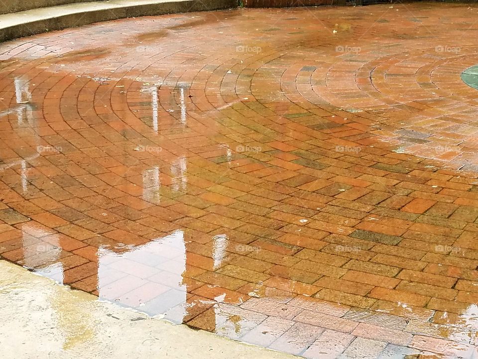 rainy day puddle reflection of building on brick pathway