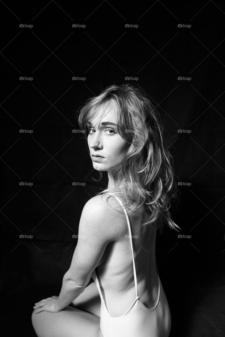 Young woman sitting on black background