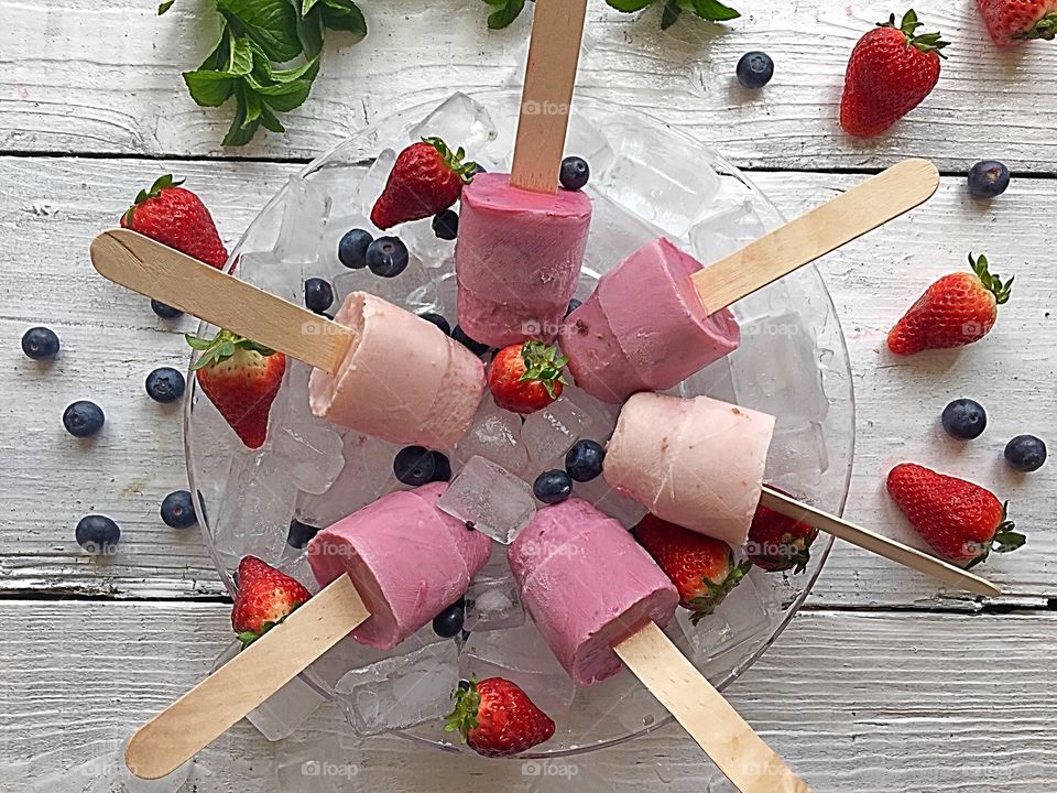 Ice lollies on bowl with berries