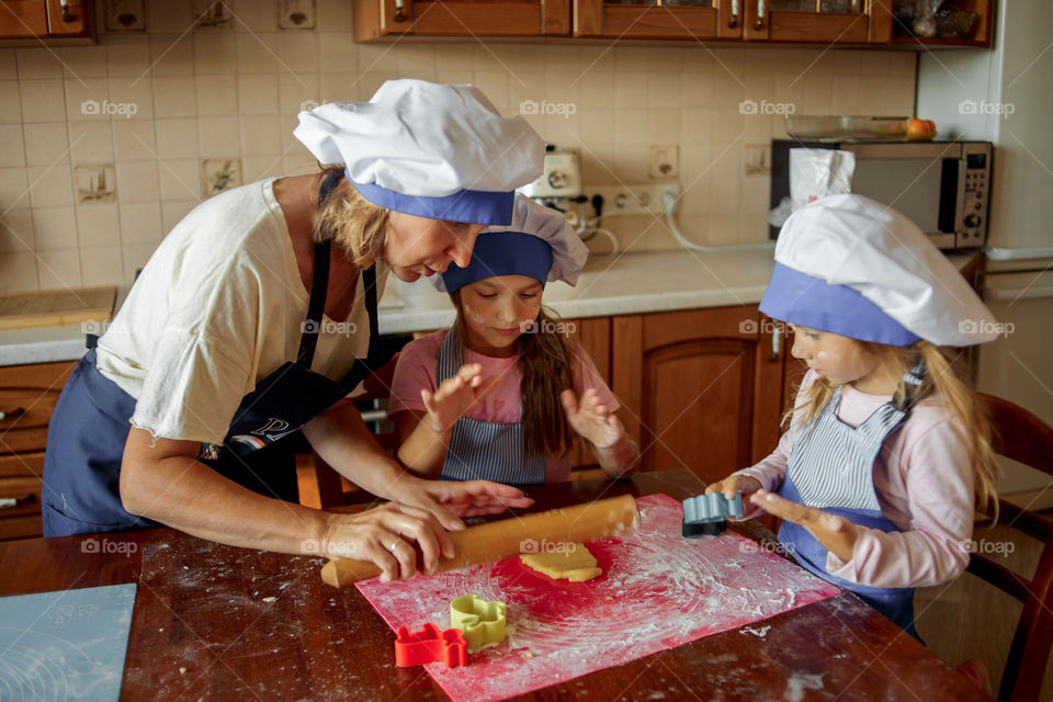 Little sisters with grandma cooking the biscuits 