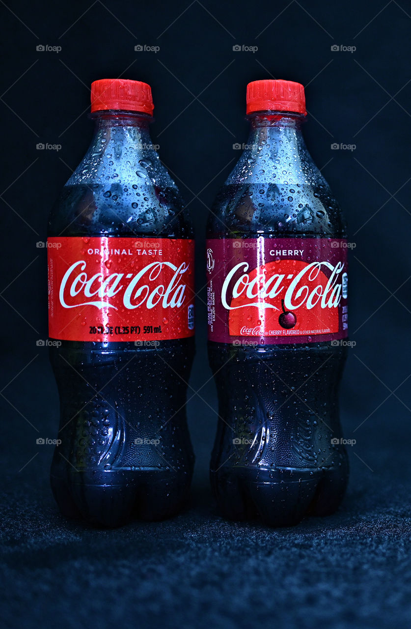 Close up shot of two Coca Cola with black background with the mists at the studio.  