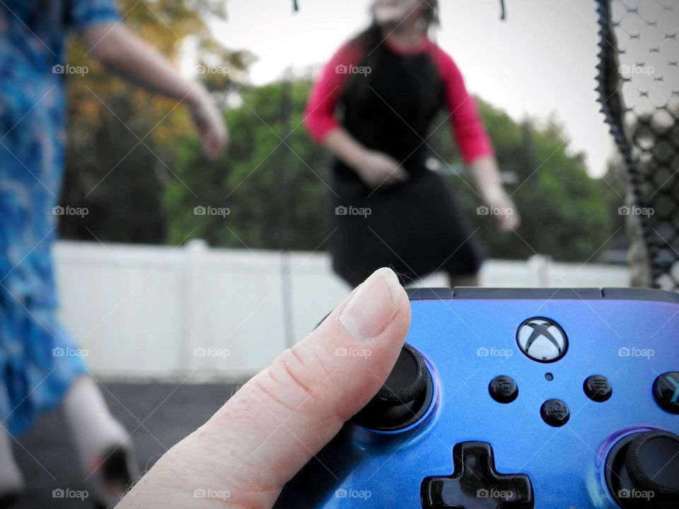 Xbox purple blue colored remote accessory used as if the mother is playing a game called: bring the children on the trampoline and play outside.