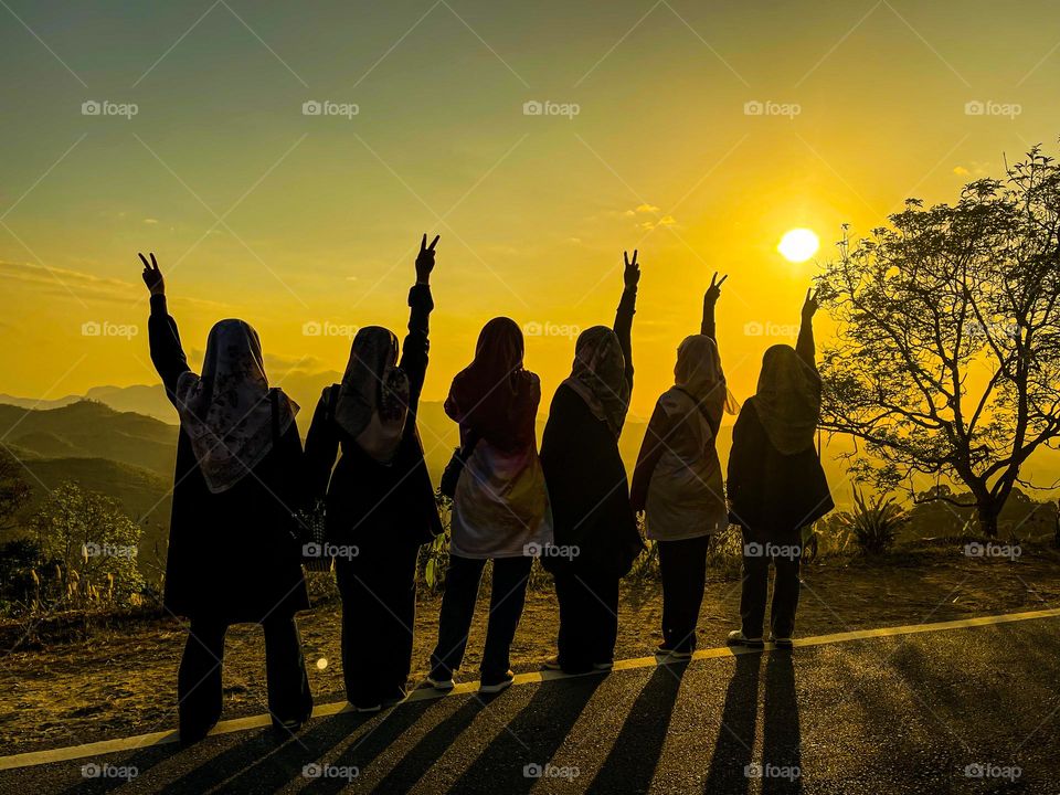 Friendship and sisterhood display on top of the mountains at sunrise with all girls up holding their arms in the air
