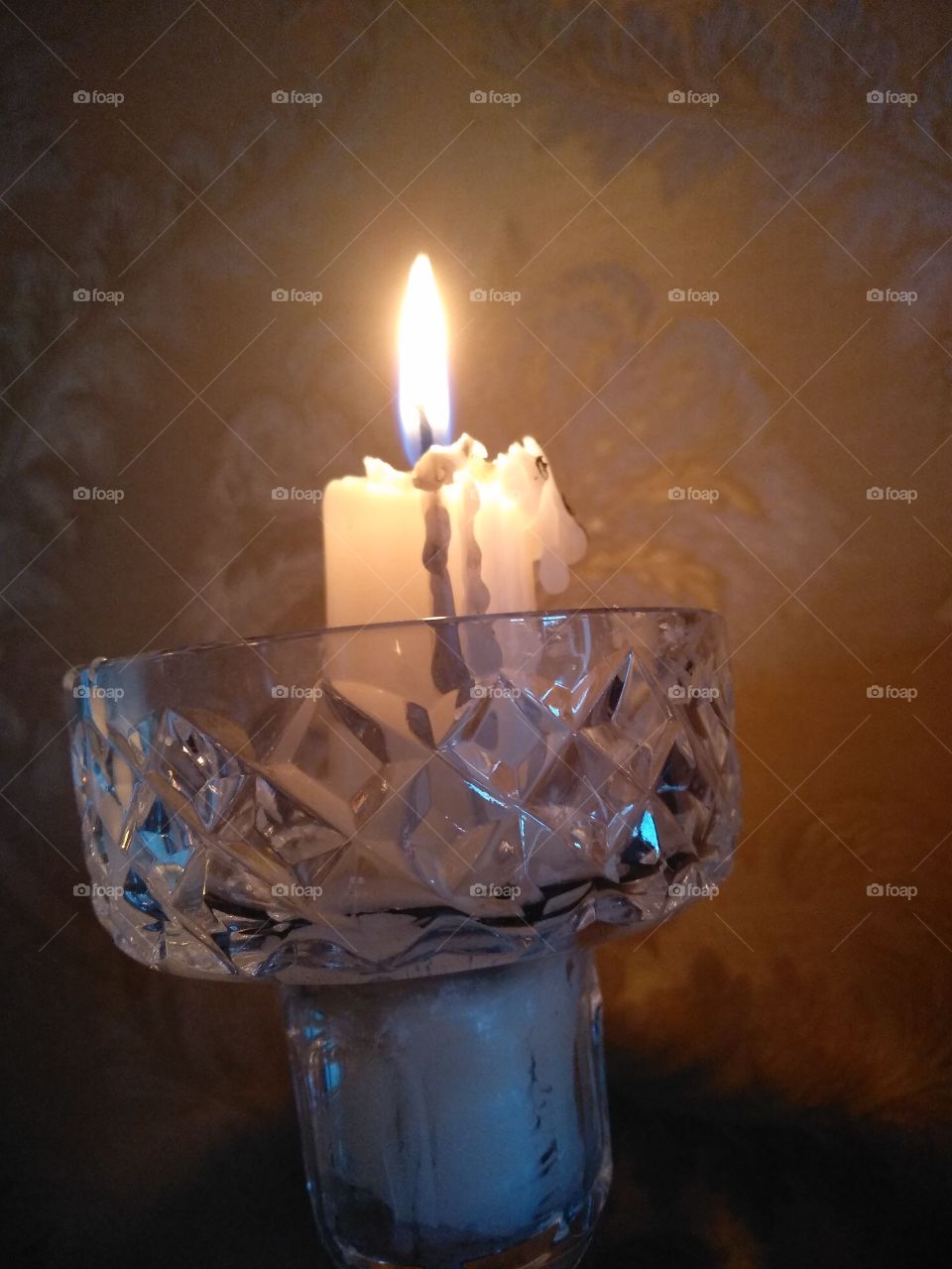 a lit candle dripping wax in a glass holder