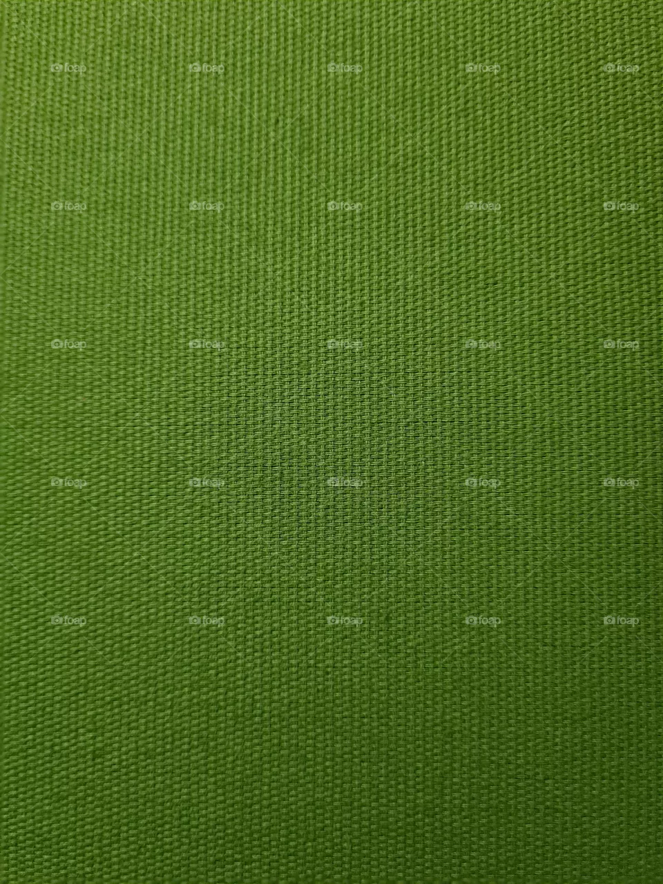 Dark green textile texture of fabric covering a bed's headboard seen from up close.