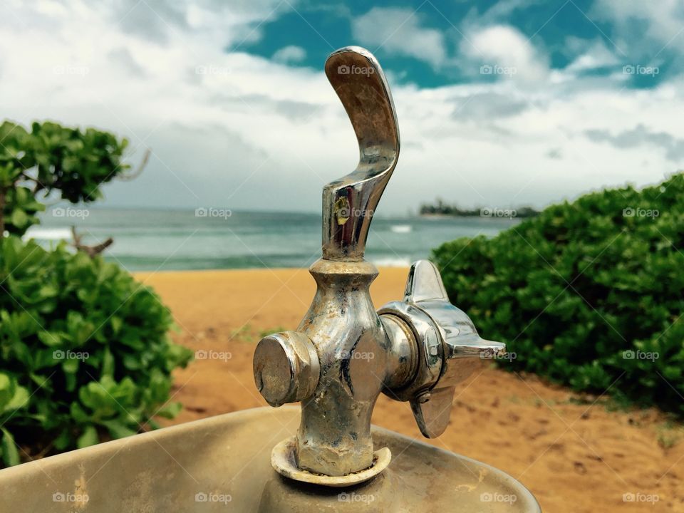 Quenched . A photo of an old water faucet on the beach.