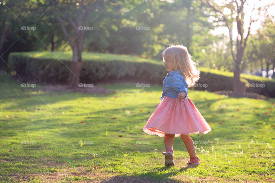 Cute little girl with blonde hair turning outdoor 