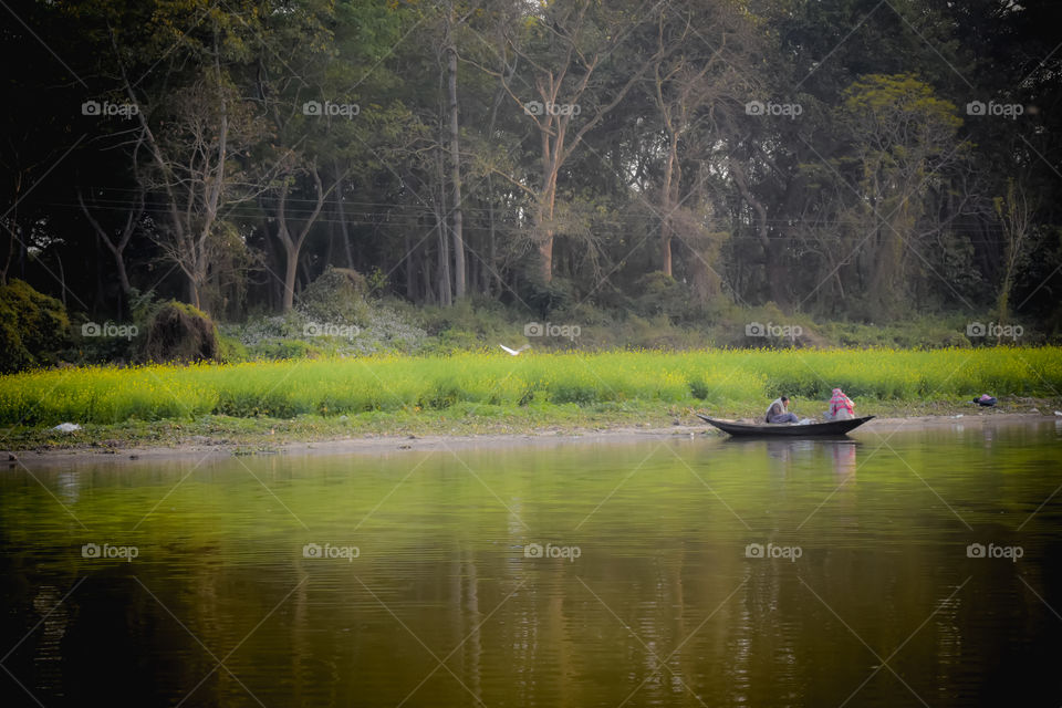 Kumari River front , Mukutmanipur Dam in Purulia West Bengal, India December 15, 2018: Fisherman sitting on a wooden boat in evening time. A beautiful landscape of rural Indian coastal village life.