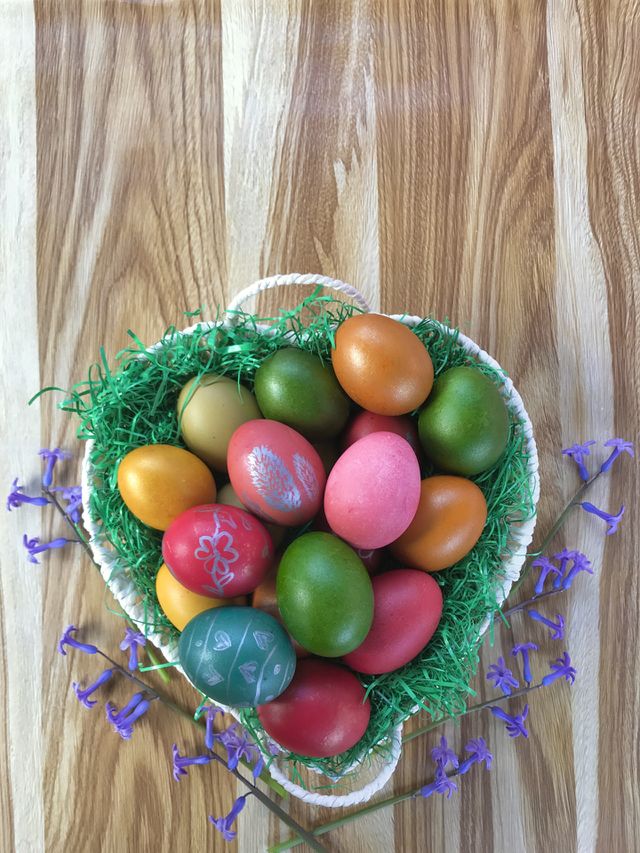 Easter is here, so in this photo you see a bascet full with colorful Easter eggs, with purple hyacint flowers.