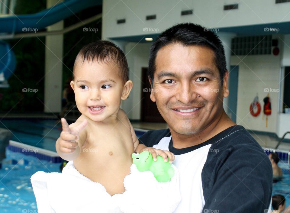 Father and his cute toddler daughter in a swimming pool