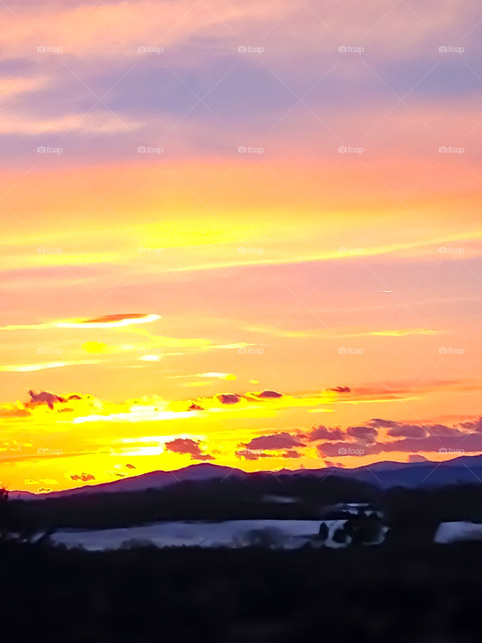 A gorgeous sunset over picturesque mountains and a field freshly laden with snow. 