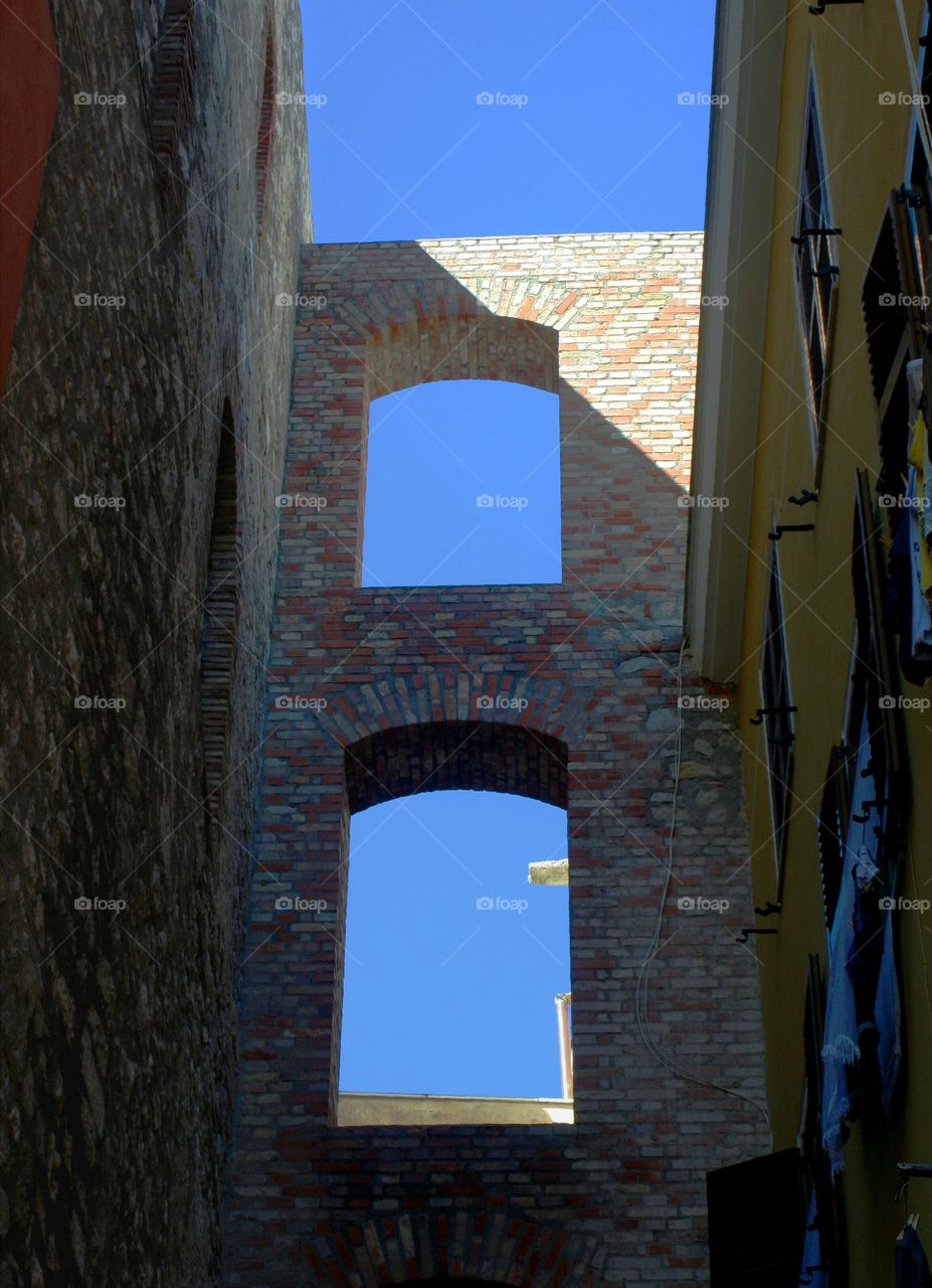 Archs in a wall let  pass the sunlight in an alley