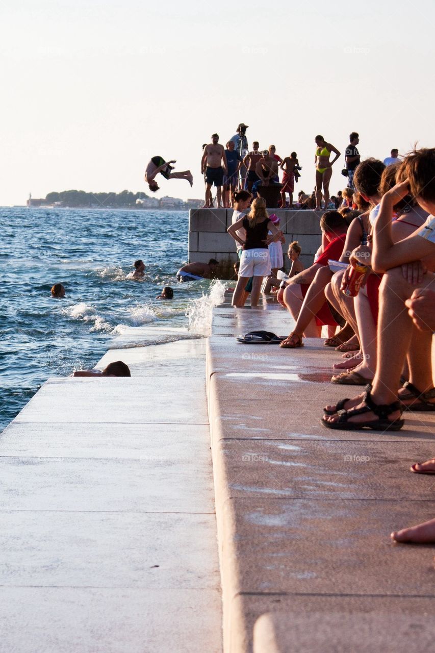 Kid jumping off the boardwalk in zadar 