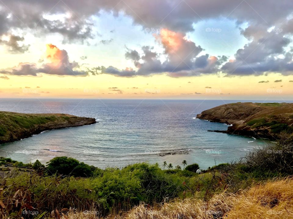 Morning sunrise paints the sky with golden hues and brings out the vibrant colors of the land and ocean (Hanauma Bay, O’ahu)