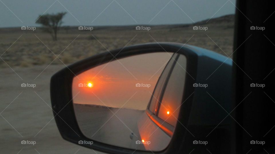 African sunset through the mirror whilst driving on the dirt roads of Namibia 