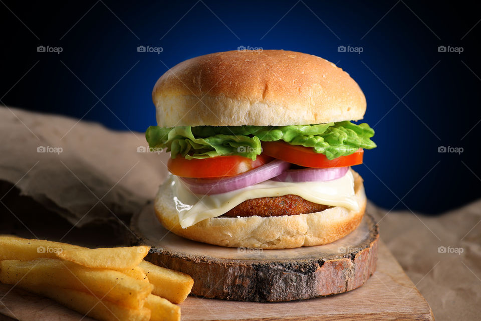 unhealthy fast food burger with French fries on a wooden platter