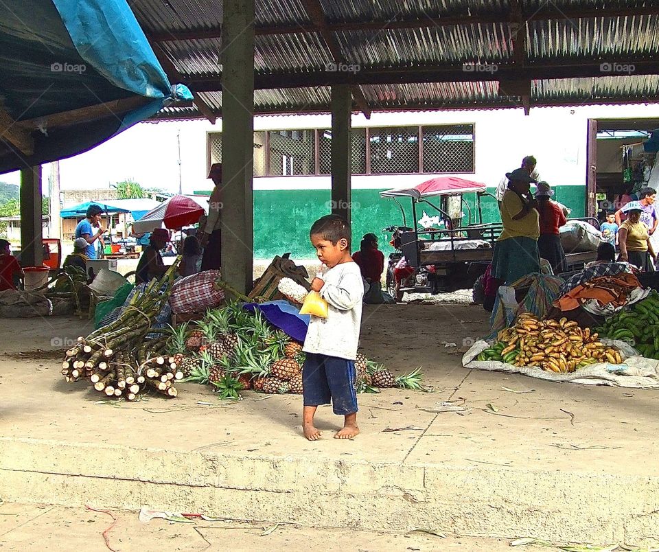 A young boy drinks orange juice from a plastic bag in Peru. 