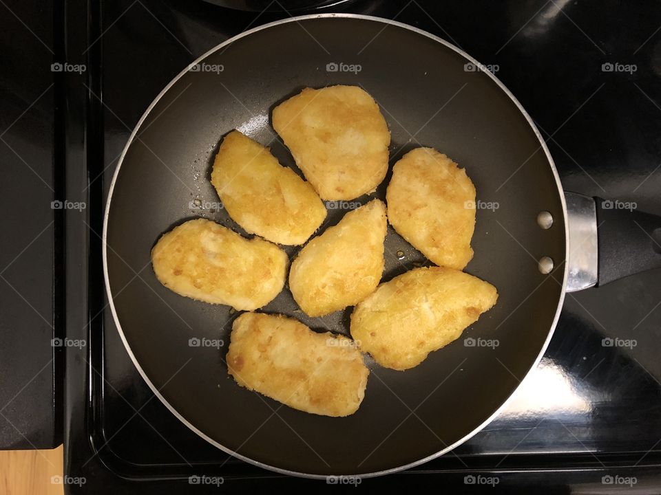 Frying battered fish in a pan.