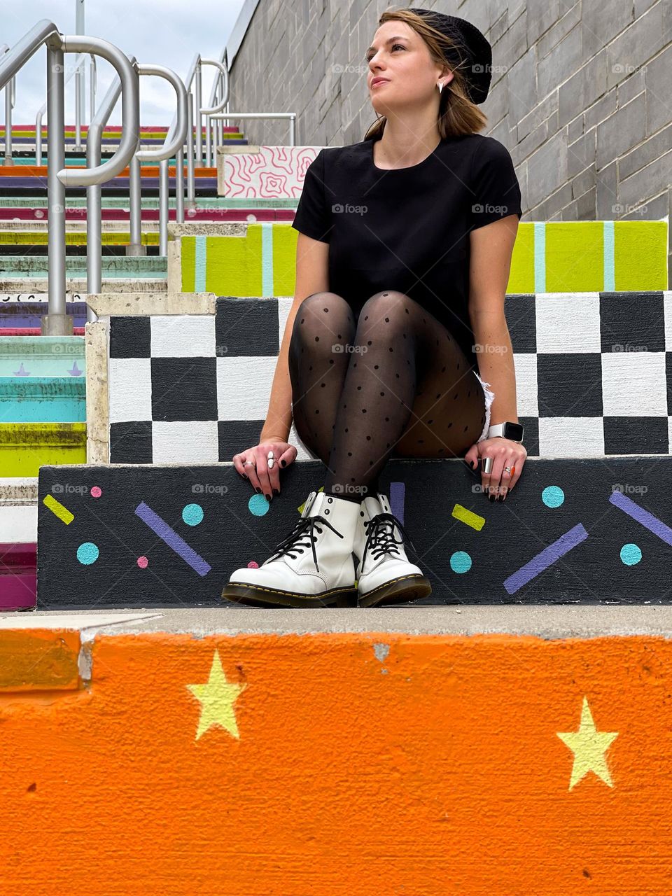 Portrait of a millennial woman sitting on colorfully painted stairs in an urban setting 