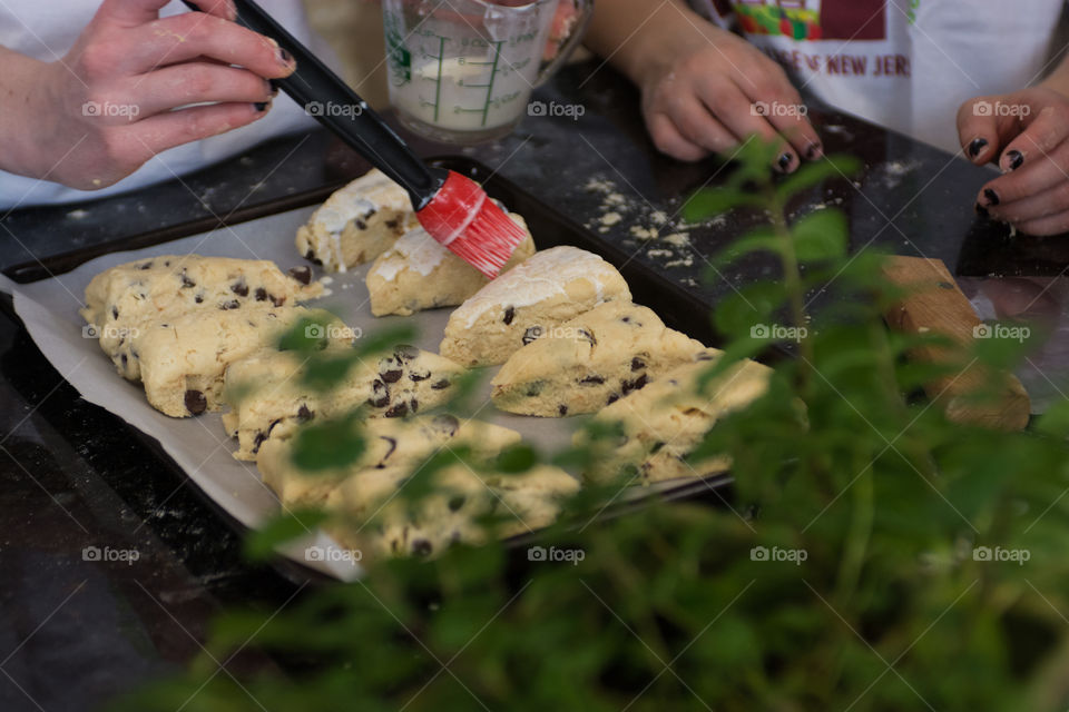 A woman is in the kitchen baking and cooking homemade scones with fruit and fresh herbs