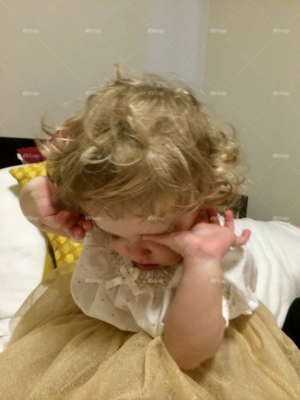 Curly blonde baby girl on bed waking up from nap in gold tutu