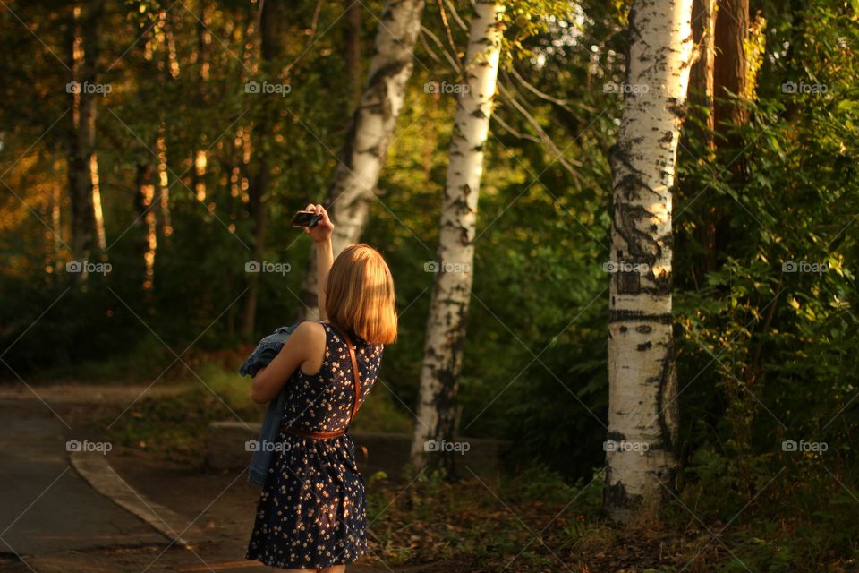Girl in a birch grove takes a selfie