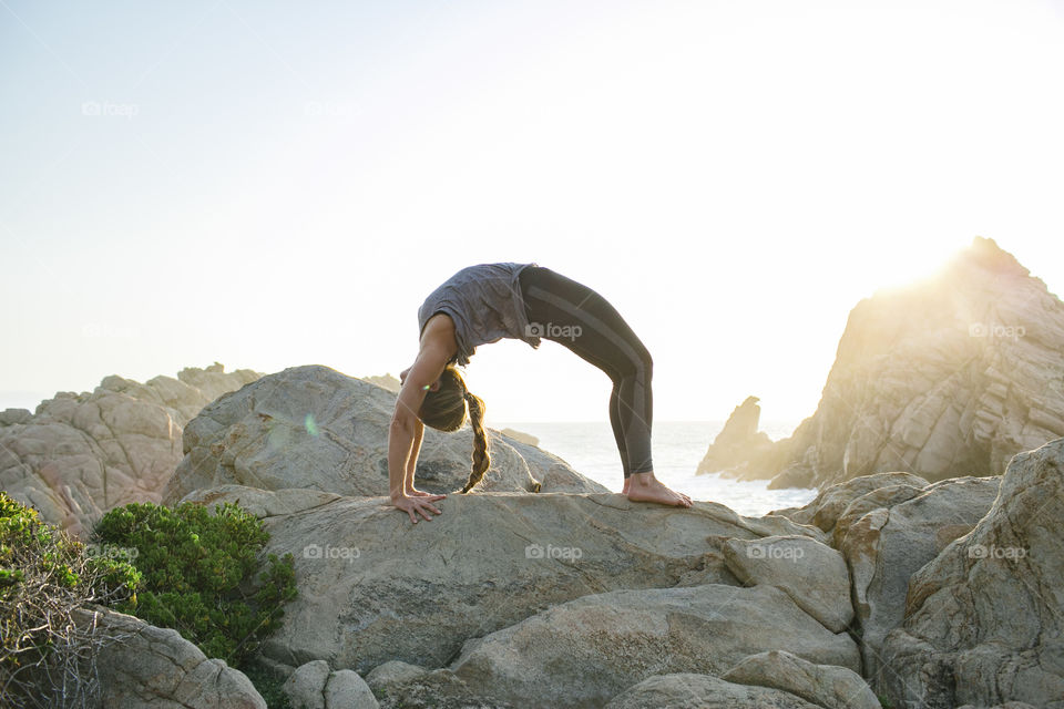 Yoga pose on the rocky coastline just before sunset 