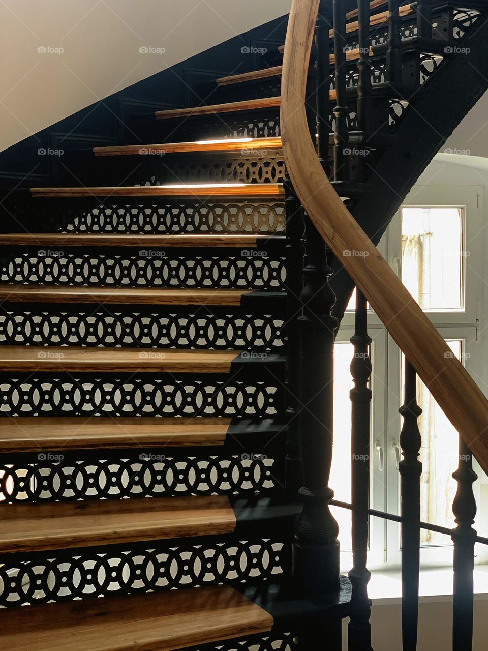 Old wooden spiral stairs in an old house, forged details, warm daylight