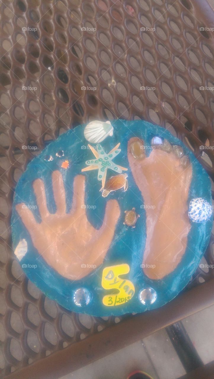 Craft project with 5yo.grandson. Made stepping stone from cement .He put his hand and foot prints on. He then added paint and tiny stones.