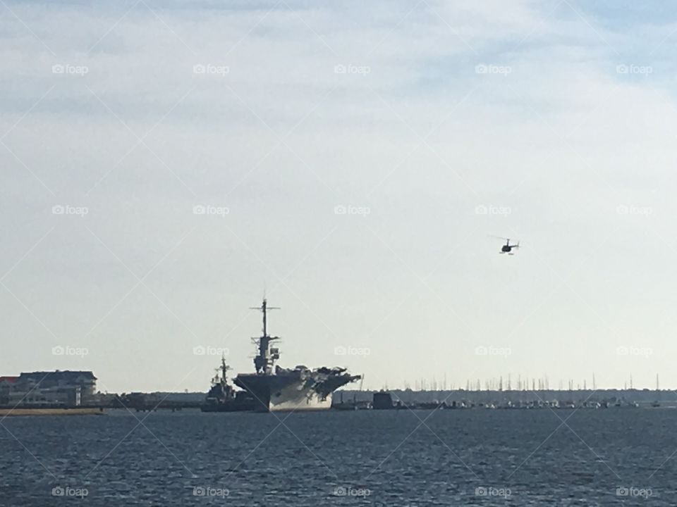 A R-44 helicopter overflies the USS Yorktown [II] CV-10, now a museum at Patriot Point, Mount Pleasant, South Carolina.