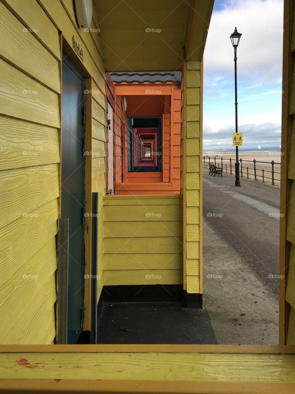 Looking through the windows of a yellow beach hut 